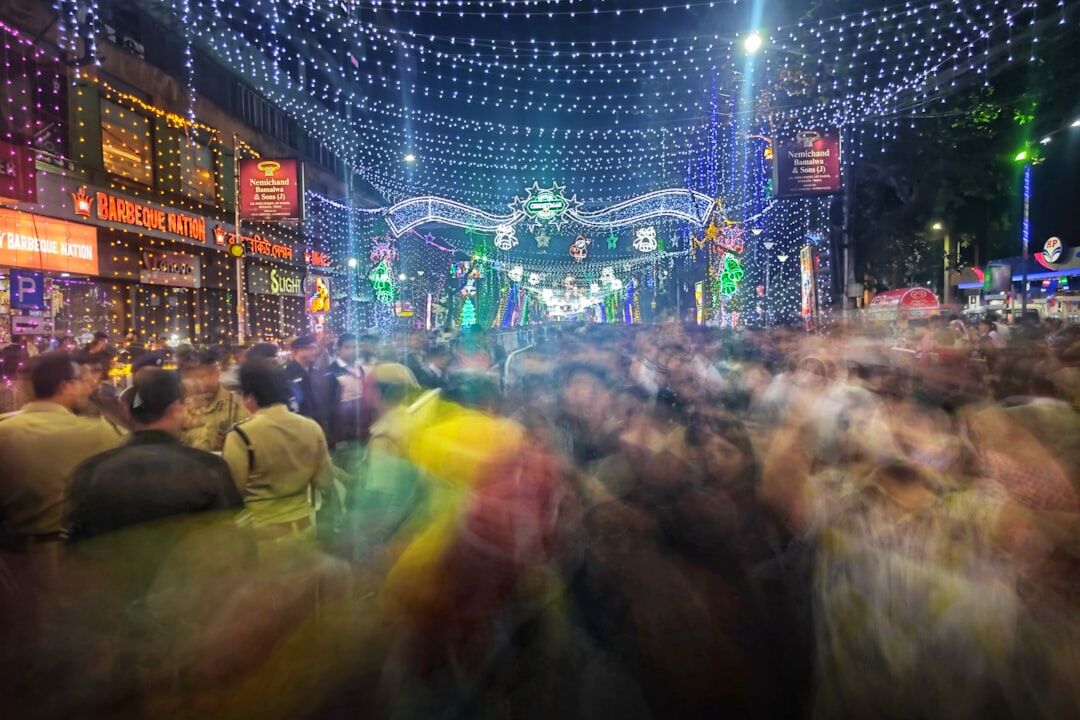 Wide shot of a crowd enjoying an evening cultural festival with stage lights